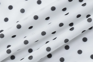 Macro detail of breathable white mesh fabric featuring classic black polka dot pattern