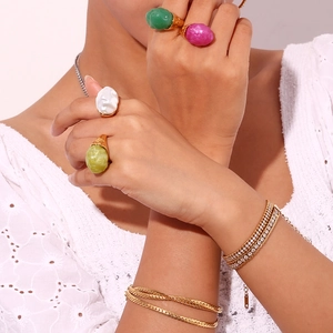 Detail of 18K gold plated rings with colorful acrylic stones and stacked bracelets