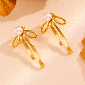 Detail of vintage gold bow earrings with pearls on a textured background