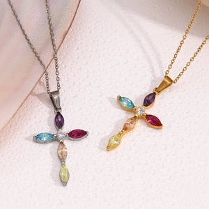 Macro shot of silver and gold cross necklaces with colorful gems on a wet surface