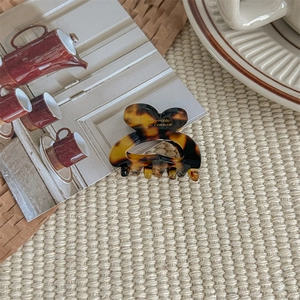 Detail of a tortoise shell heart hair claw clip with gold engraving on a woven mat