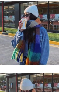 Close-up of rainbow plaid tassel scarf and white knit beanie in winter street style