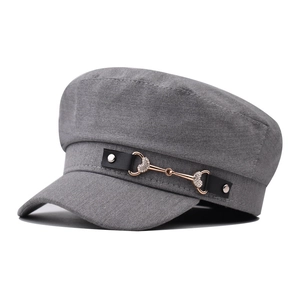 Detailed view of grey military cap featuring a leather strap and heart-shaped crystal horsebit