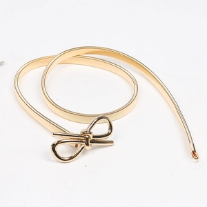 Detailed view of a gold elastic metal belt featuring a sleek metallic bow buckle