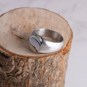 Polished silver titanium steel signet ring displayed on a natural rustic wooden base
