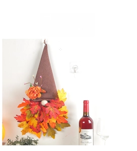 Close-up of autumn gnome wall decor with burlap hat and maple leaf beard on white wall