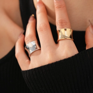 Detailed close-up of wide concave mirror-finish minimalist rings in gold and silver