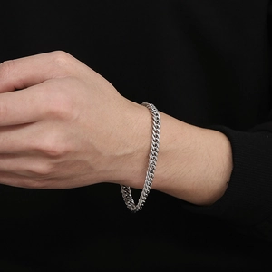 Bracelet gourmette en acier titane argenté avec fermoir à bascule porté au poignet mixte