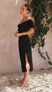 Détail de la robe élégante en satin noir à épaules dénudées avec manches à volants