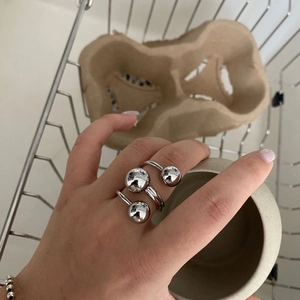 Close-up of three-layered silver ring with large beads worn on hand in natural lighting