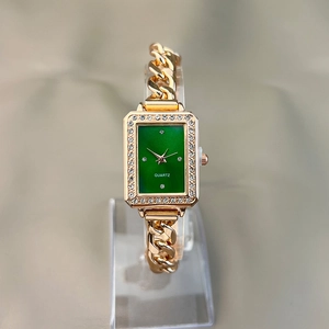 Detail of square green dial watch with gold chain band and rhinestones on display