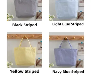 Detail view of large striped canvas tote bags in black, blue, yellow, and navy colors