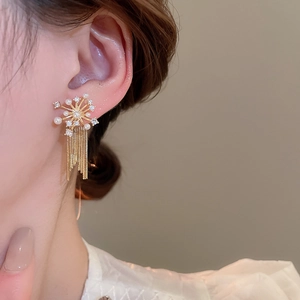 Detail view of fireworks tassel earrings with pearls and zircons worn by a model