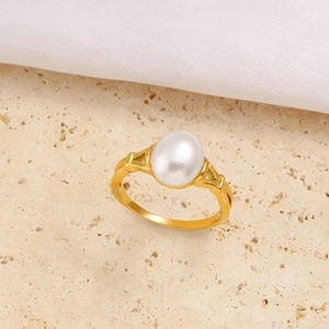 Elegante anello in acciaio dorato con perla bianca ovale in una montatura a griffe
