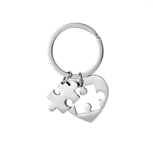 Polished stainless steel heart and puzzle piece keychain set for couples on white background