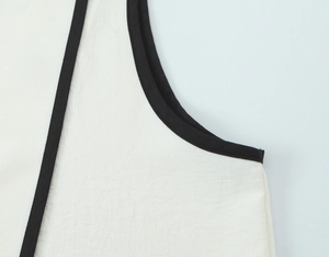 Detailed close-up of white crepe top with contrasting black piping trim and fabric texture