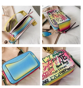 Detail of gradient rainbow crossbody bag with graffiti print and dual zipper compartments