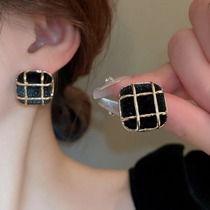Close-up of square black and gold grid pattern earrings with model's wearing view
