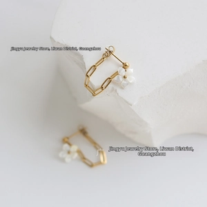 Macro shot of 18K gold plated chain earring with a delicate white shell flower detail