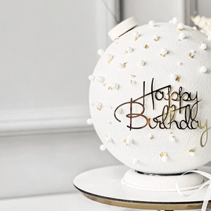 Detail of white birthday cake with gold foil flakes, pearls and Happy Birthday acrylic topper