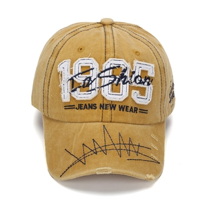 Detail of vintage yellow cap with 1985 embroidery and distressed denim brim details