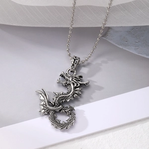 Detailed view of a silver dragon pendant with scales and wings on a beaded chain