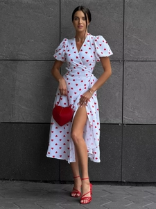 Detail of white wrap dress with red heart print, puff sleeves and high slit design