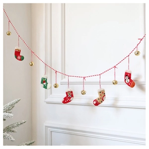 Close-up of wool felt Christmas stockings and gold bells hanging on a red cotton cord