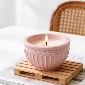 Pink embossed flower ceramic candle bowl with relief texture on a wooden tray