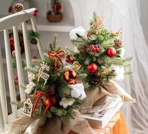 Close-up of a mini Christmas tree with wooden ornaments and warm knitted textures