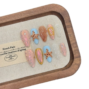 Handmade ocean-themed press-on nails with 3D starfish and shell textures on wood display