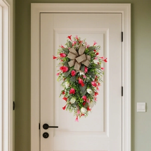 Floral teardrop swag with pink flowers, greenery, and burlap bow hanging on a white door