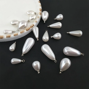Macro shot of white teardrop faux pearl pendants with silver loops for DIY jewelry