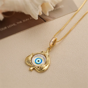 Close-up of golden Devil's Eye spade pendant on beige fabric and magazine
