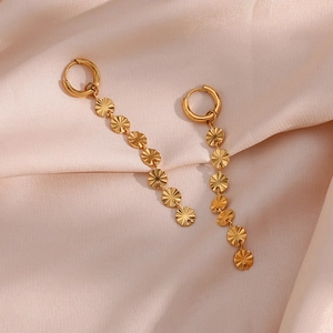 Detailed close-up of gold dangle earrings with sunburst disks on silk fabric