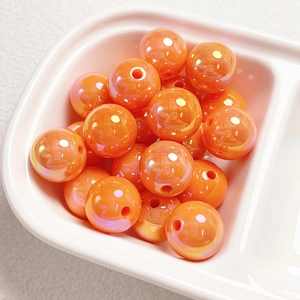 Close-up of glossy orange acrylic pearlescent round beads for DIY jewelry making