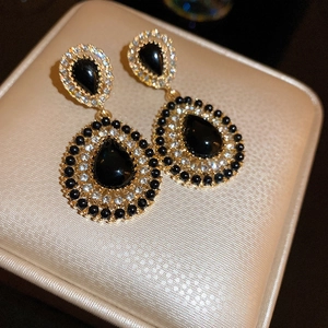 Vintage black teardrop earrings with crystals on a golden jewelry box display