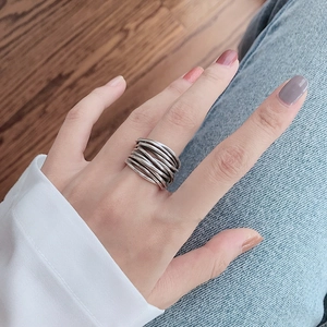 Detailed view of a silver multi-layer wrap ring worn on a finger in a casual setting