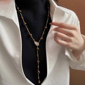 Detail of tiger eye stone necklace with zircon leaf pendant on a golden chain
