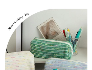 Detail of tweed texture pencil cases in pastel green, cream, and blue with white zippers