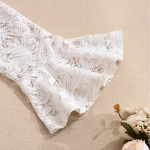 Close-up of white floral lace fabric texture with elegant cutout details and soft finish