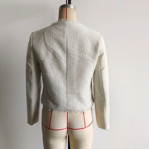 Detail der Tweed-Textur und Fransenverzierung an der Rückseite der cremefarbenen Jacke