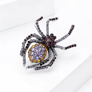 Detailed macro view of vintage spider brooch with colorful rhinestones on white geometric block