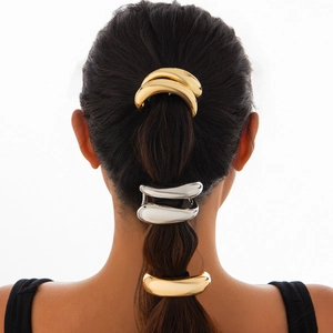 Close-up of golden and silver curved metal hair ties worn on model's hair