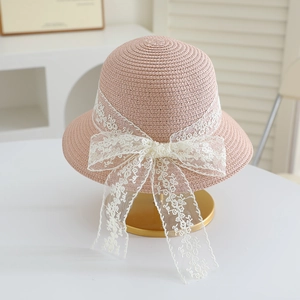 Close-up of pink straw hat featuring intricate lace bow and floral embroidery details
