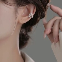 Macro shot of a silver layered snake ear cuff with zircons worn on the helix cartilage