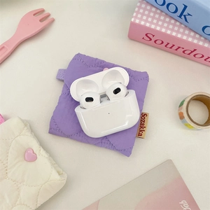 Detail view of purple quilted fabric storage pouch with wireless earbuds and heart charm