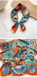 Detail of silk-feel square scarf with vintage orange and blue floral pattern on wood tray