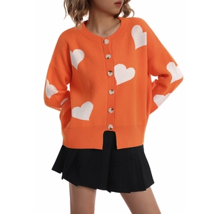 Detail of orange knitted cardigan with white heart patterns and single breasted buttons