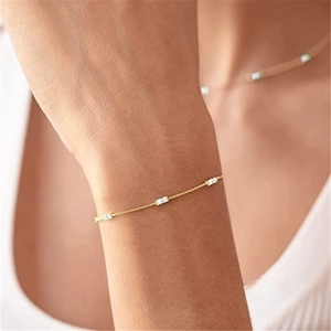 Detail of a thin gold chain bracelet with three rectangular cubic zirconia stones on a wrist